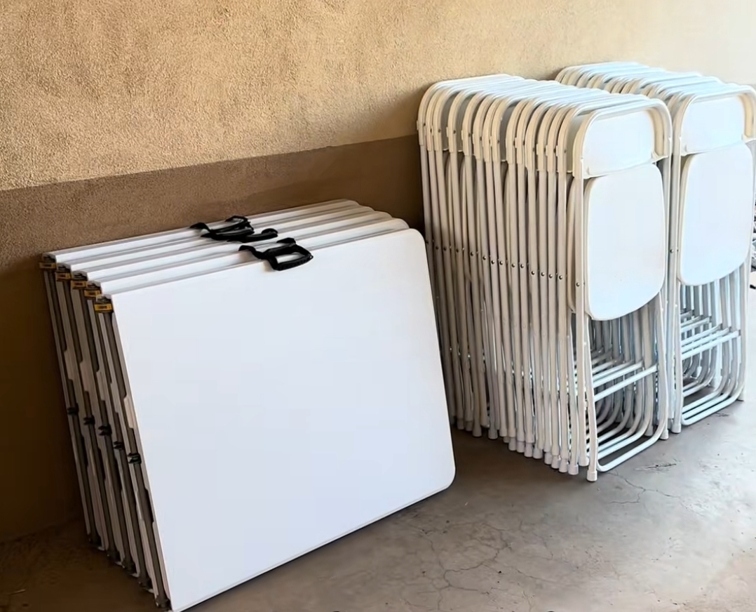 Stacks of white folding tables and chairs strapped and ready to load