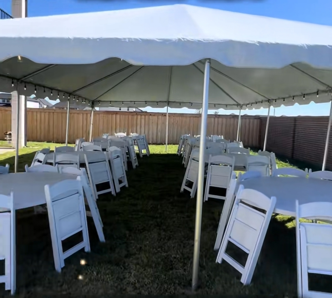 White backyard canopy tent with round tables and chairs on grass in daylight