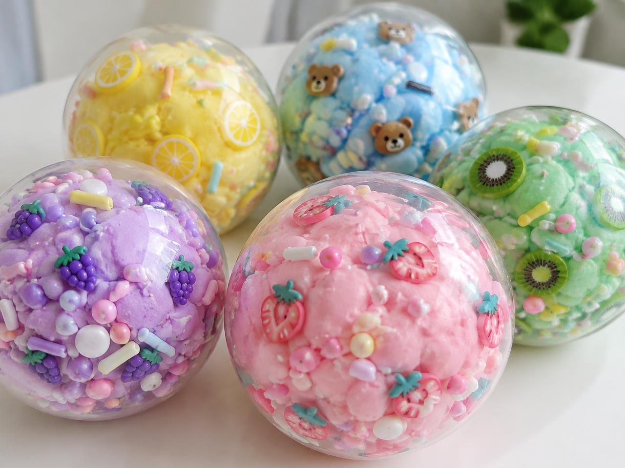 Styled example of clear squishy balls filled with pastel dough and fruit toppings